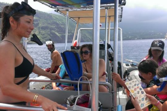People in a boat with snorkel gear, preparing for a dive near a scenic coastline.