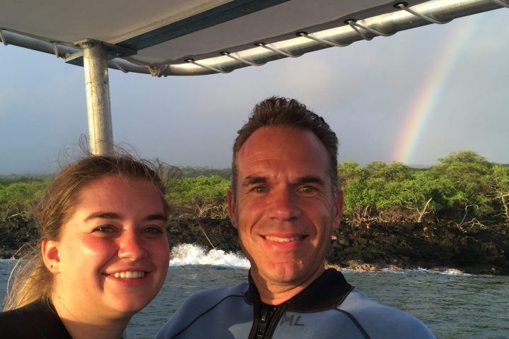 a person standing next to a body of water posing for the camera